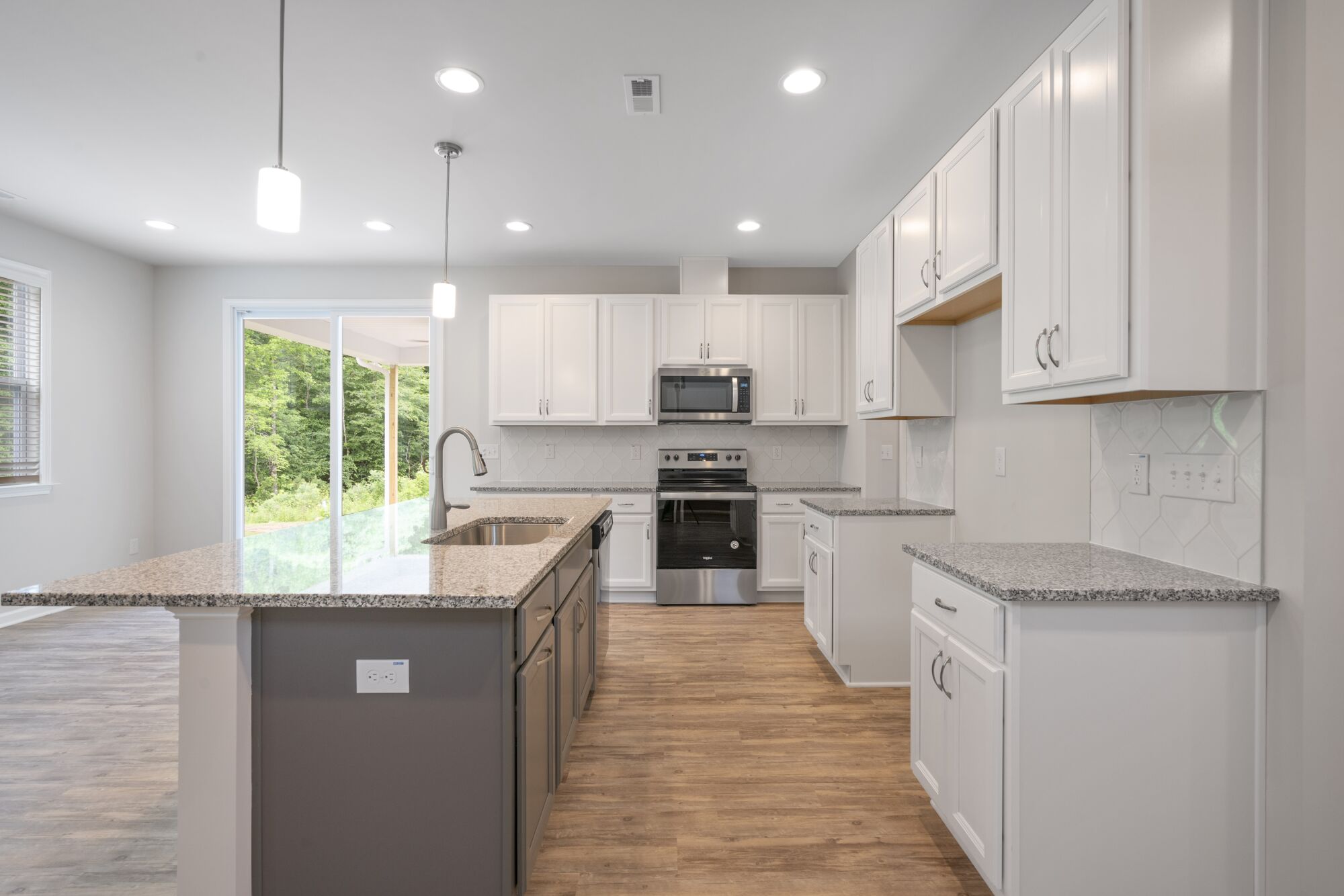 L-Shaped Kitchen with door, pendant light, white cabinets, window, wood flooring and dark wood cabinets
