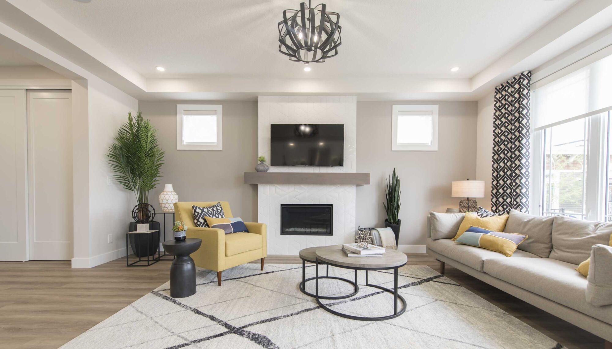 Living room with a beige couch, a pale yellow armchair, a television, and a fireplace.