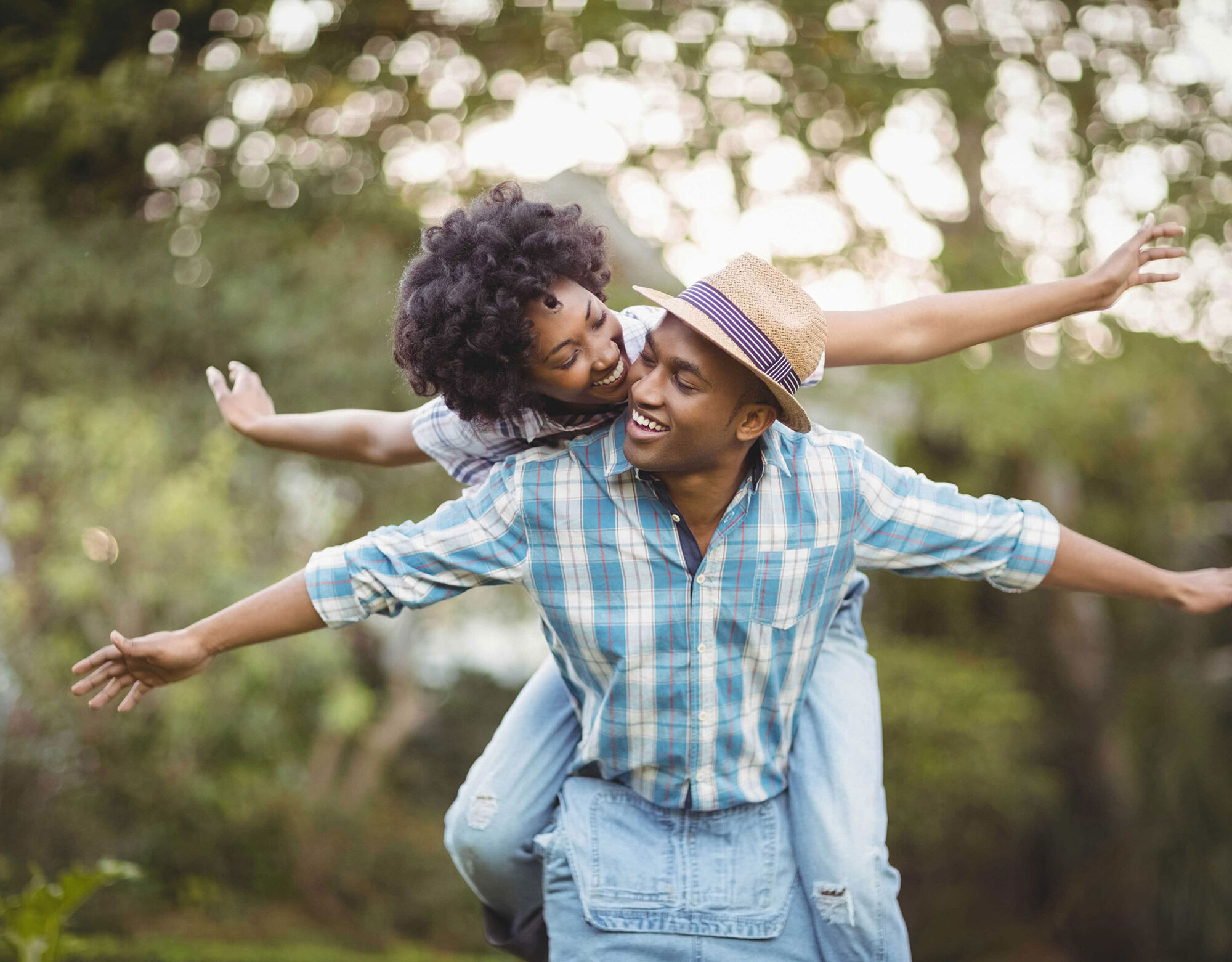 A woman piggybacking on a man with their arms swung out to the sides.