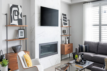 Living room with a grey L-shaped couch surrounding a black marble coffee table.