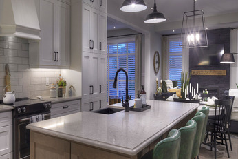 Kitchen with island with black faucet and white vertical cabinets to the left. 