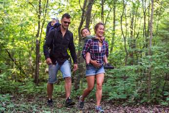 Family of four hiking in a forest surrounded by greenery. 