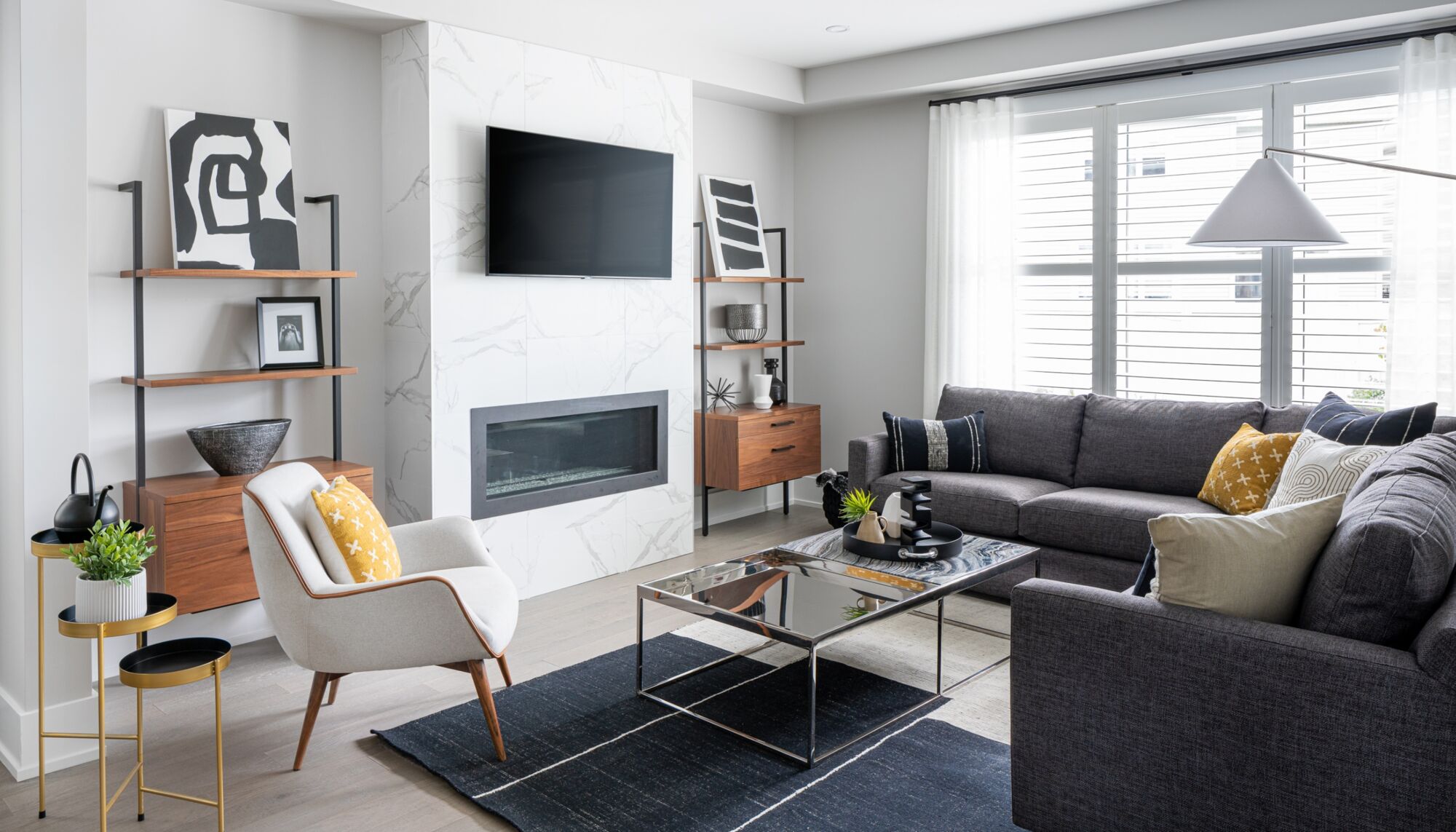 A white furnished living room with a wall mounted television and fireplace.