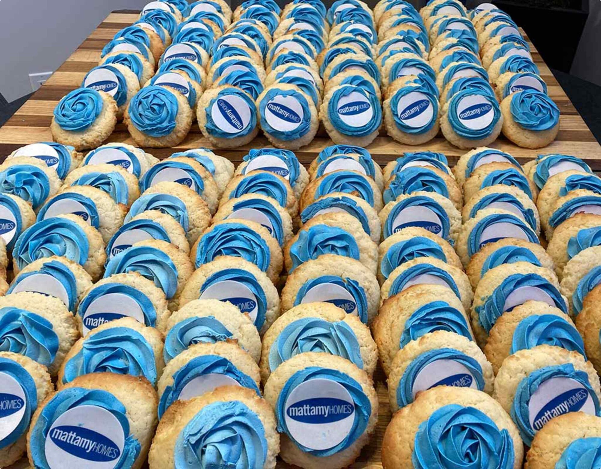 Several rows of cookies with the the blue Mattamy Homes logo on them with icing behind it.