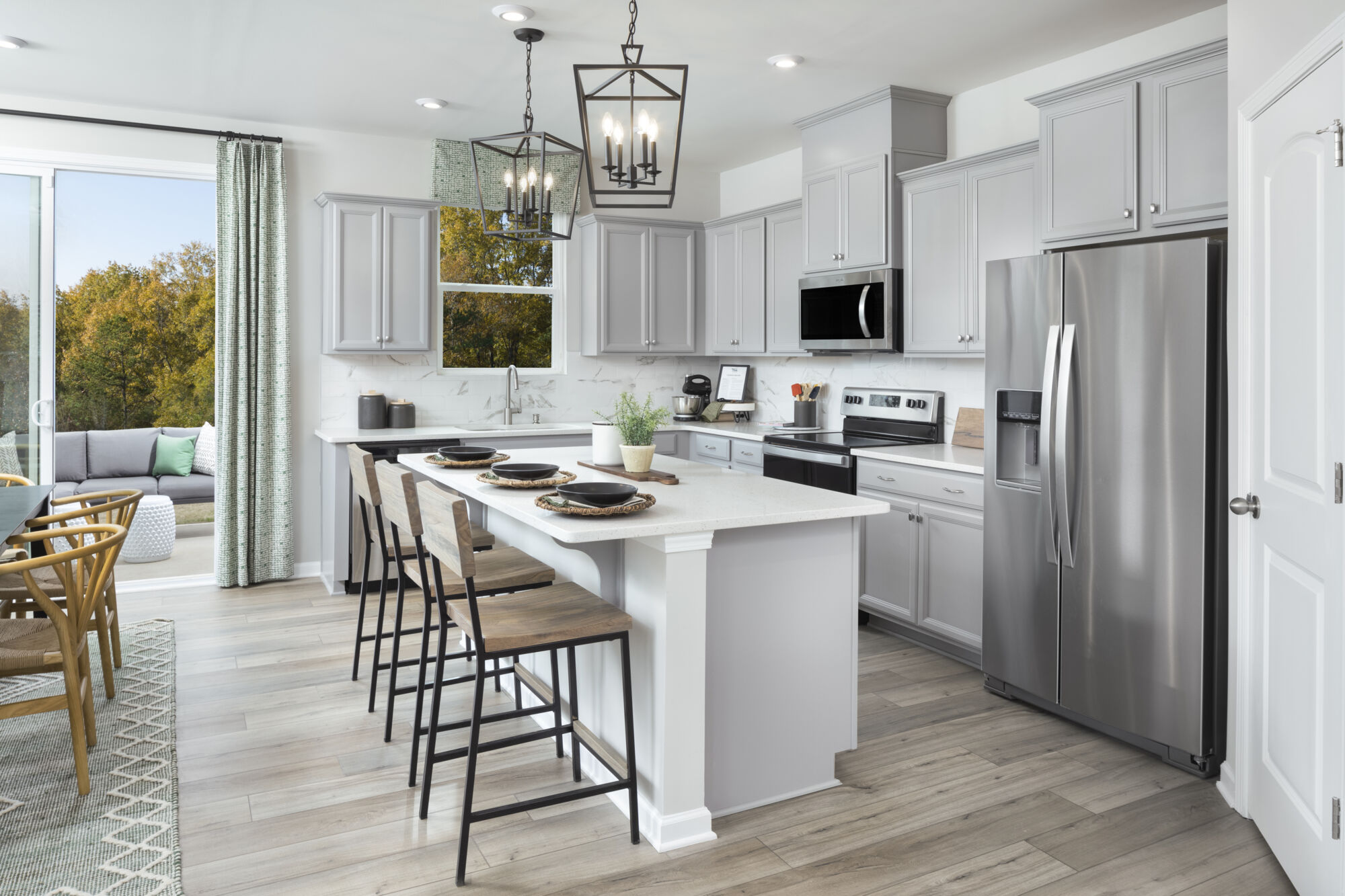 L-Shaped Kitchen with window, door, pendant light, curtains, refrigerator, range, white cabinets and wood flooring