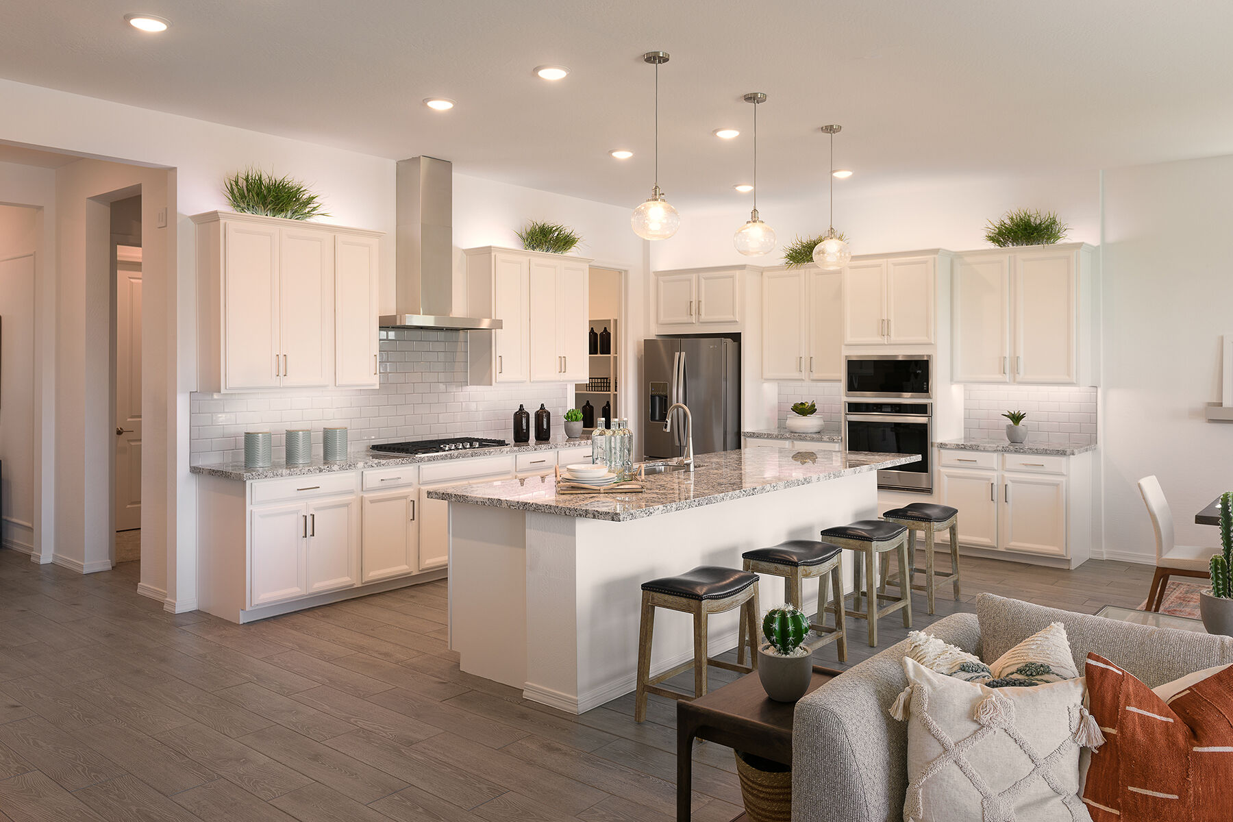 L-Shaped Kitchen with oven, pendant light, refrigerator, cooktop, wood flooring and white cabinets