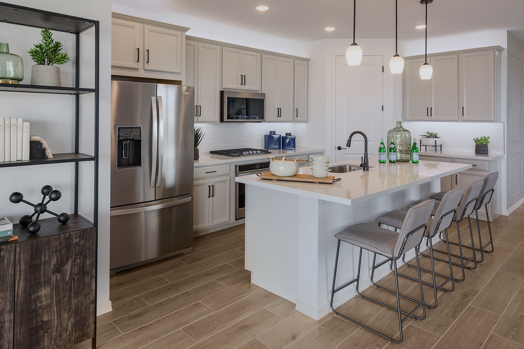 L-Shaped Kitchen with refrigerator, pendant light, door, cooktop, wood flooring and white cabinets