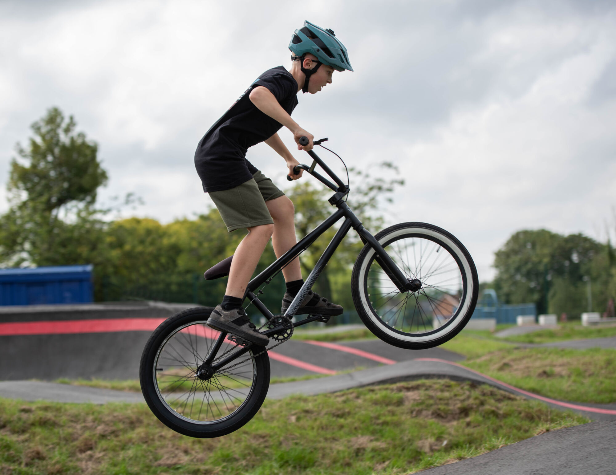 Child doing a jump on a BMX bike in a pump track park