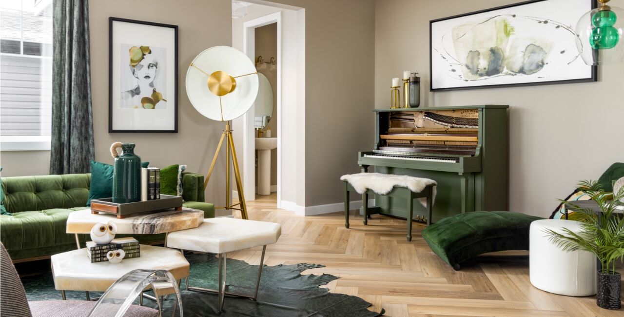 Living room area with a green and brown piano, green couches and studio lighting.
