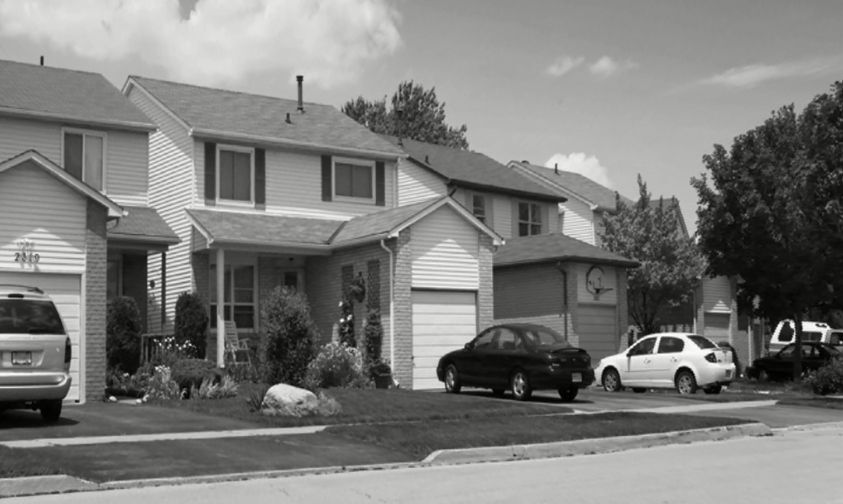 Exterior of four single-family homes with front-facing, single-car garages and cars on the driveway.