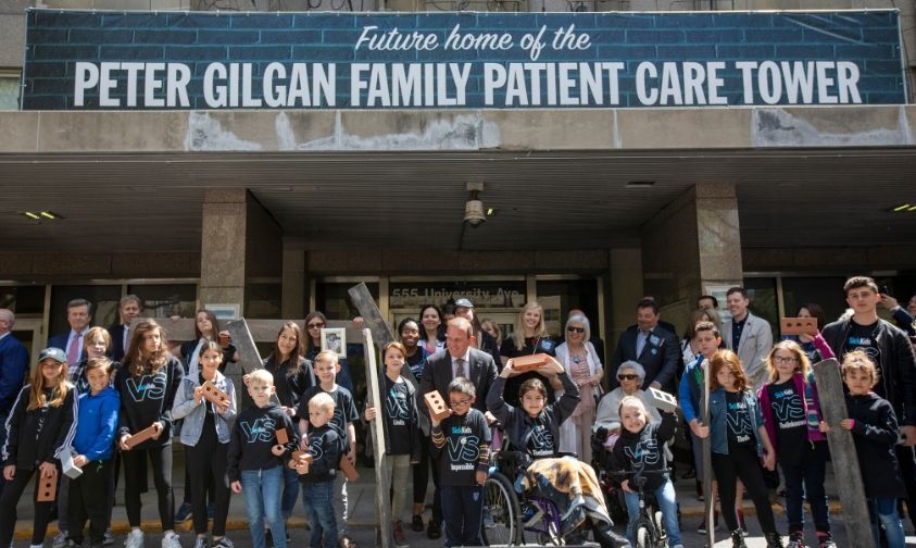 Founder of Mattamy Homes, Peter Gilgan, outside of the future Peter Gilgan Family Patient Care Tower, surrounded by patients and their families.