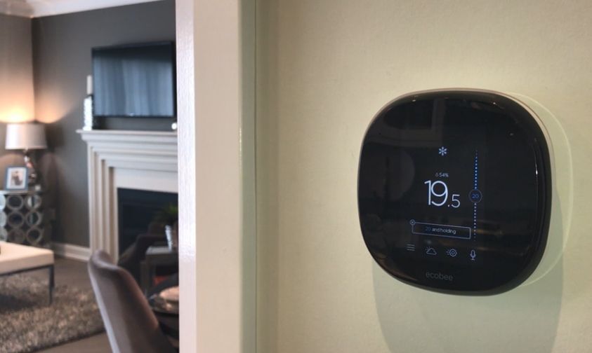 Ecobee smart thermostat on a beige wall by the living room.
