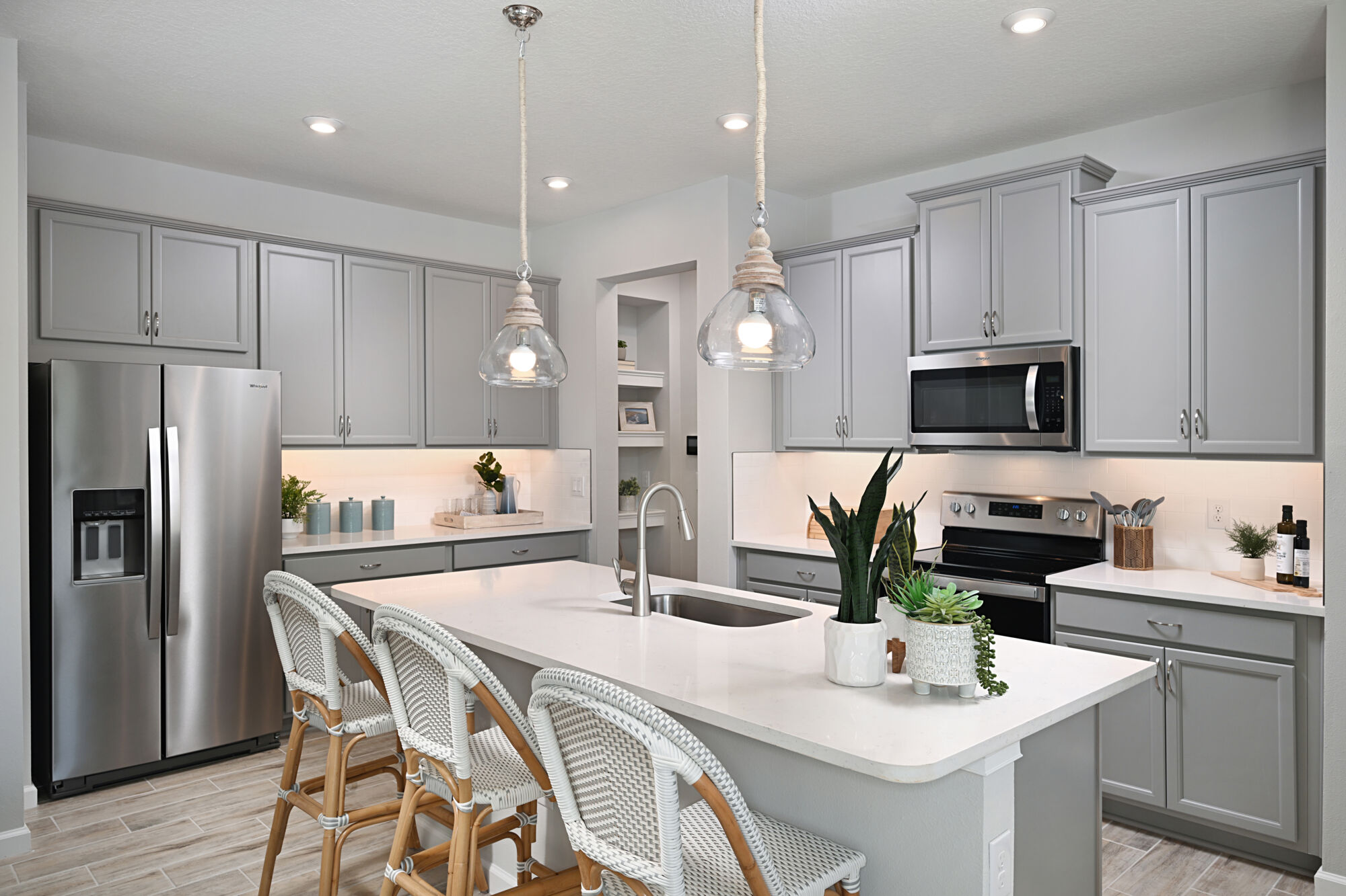 L-Shaped Kitchen with refrigerator, range, pendant light, tile flooring and white cabinets