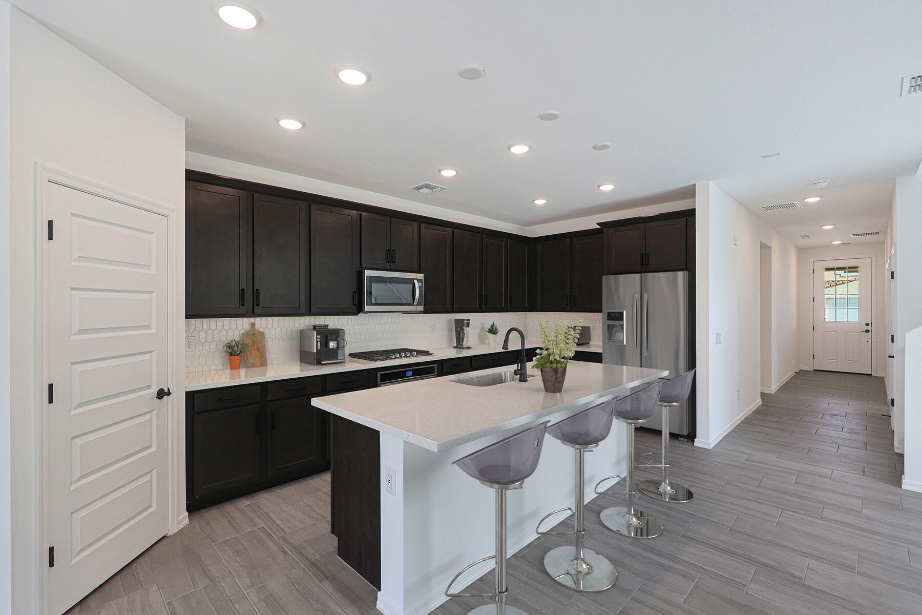 L-Shaped Kitchen with door, refrigerator, cooktop, dark wood cabinets and wood flooring