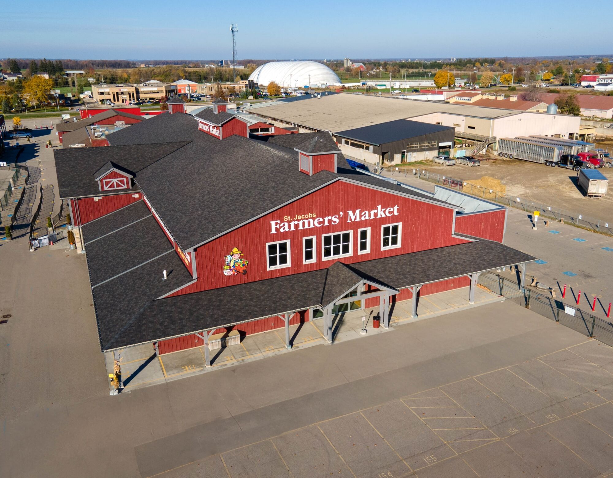 A red farmers market building with a warehouse in the background