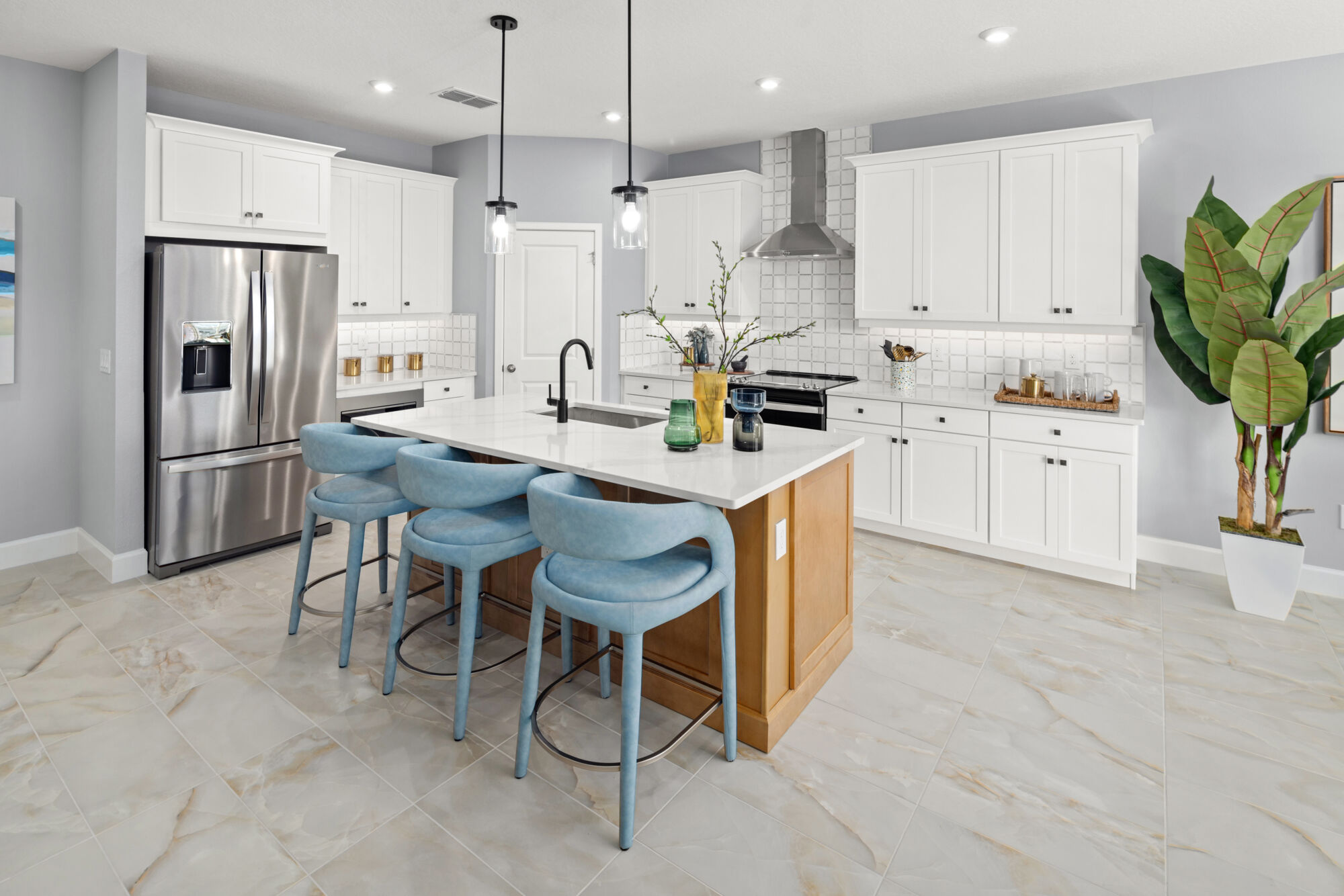 L-Shaped Kitchen with refrigerator, pendant light, door, range, white cabinets and tile flooring