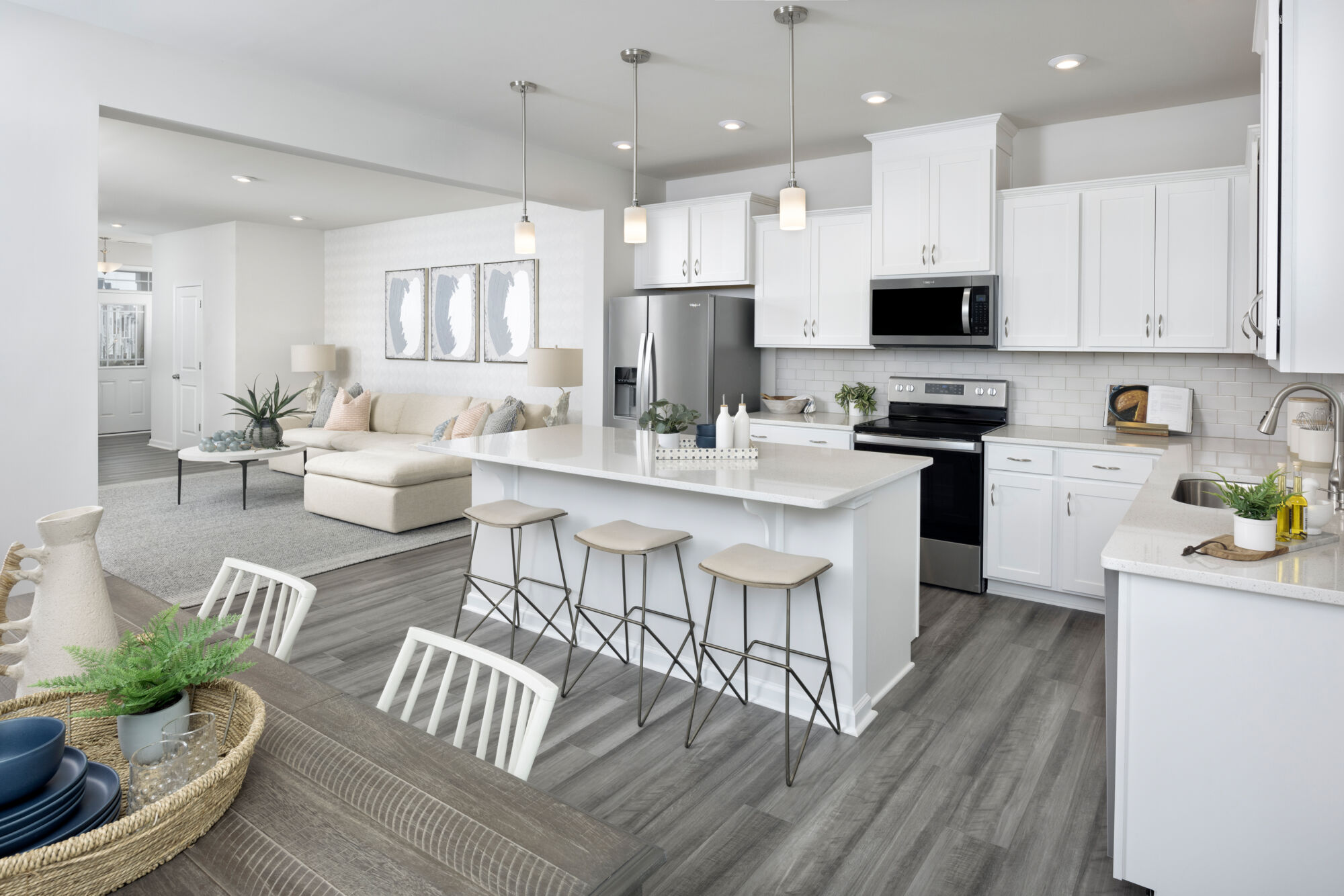 L-Shaped Kitchen with pendant light, range, door, painting, refrigerator, white cabinets and wood flooring