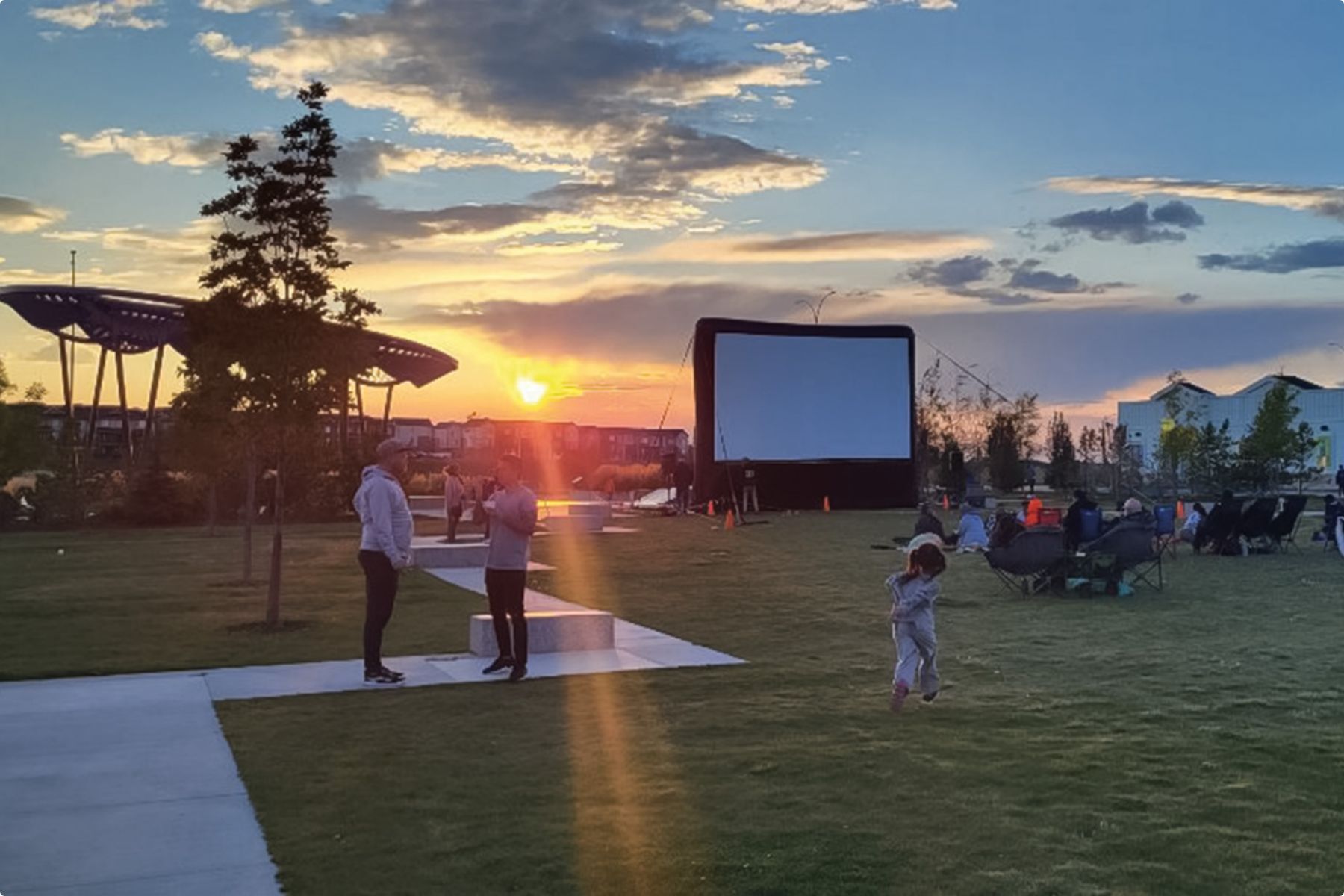 Outdoor park setting, sunset and families, movie screen
