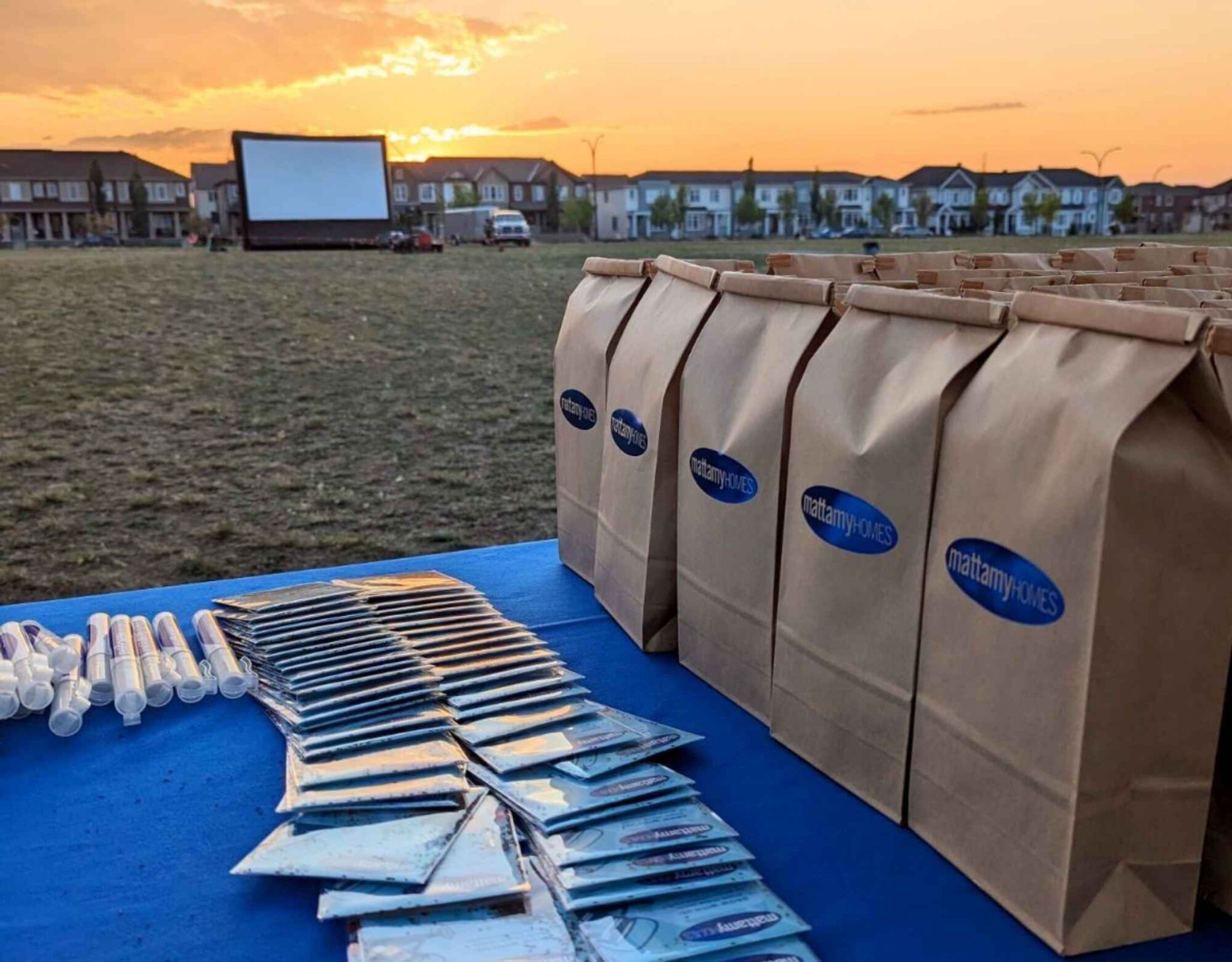 Event table with paper bags in a park, movie screen in background