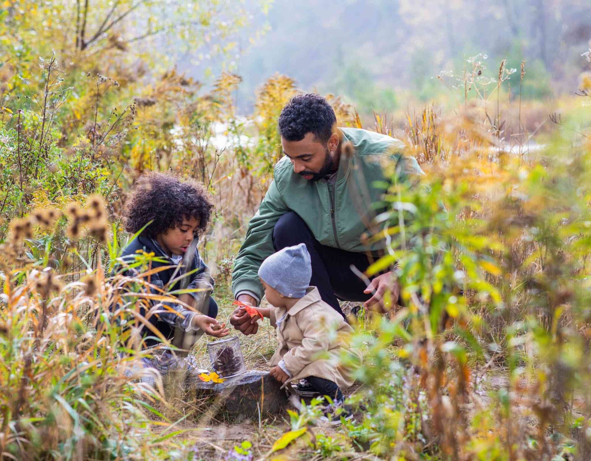 man and two young children playing outdoors in nature