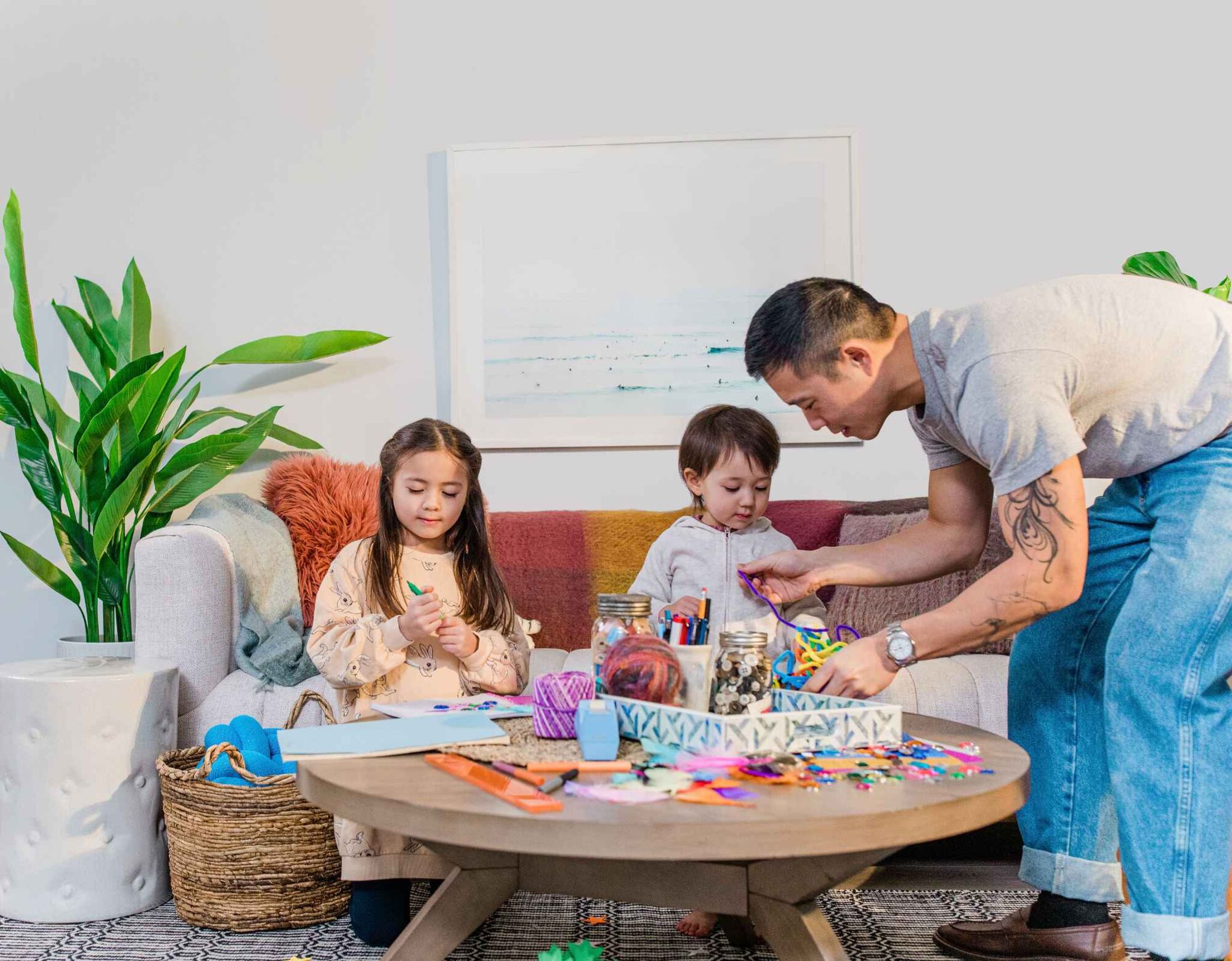 Man with two young children playing inside at coffee table