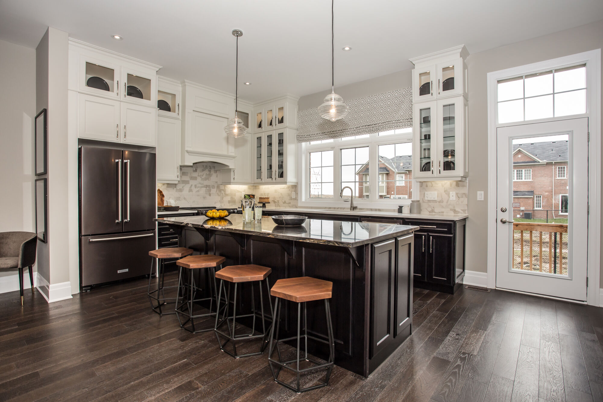 Kitchen with 2 tone cabinets, dark and white, dark countertops, steel appliances, pendant lights, kitchen window, with backyard door on right