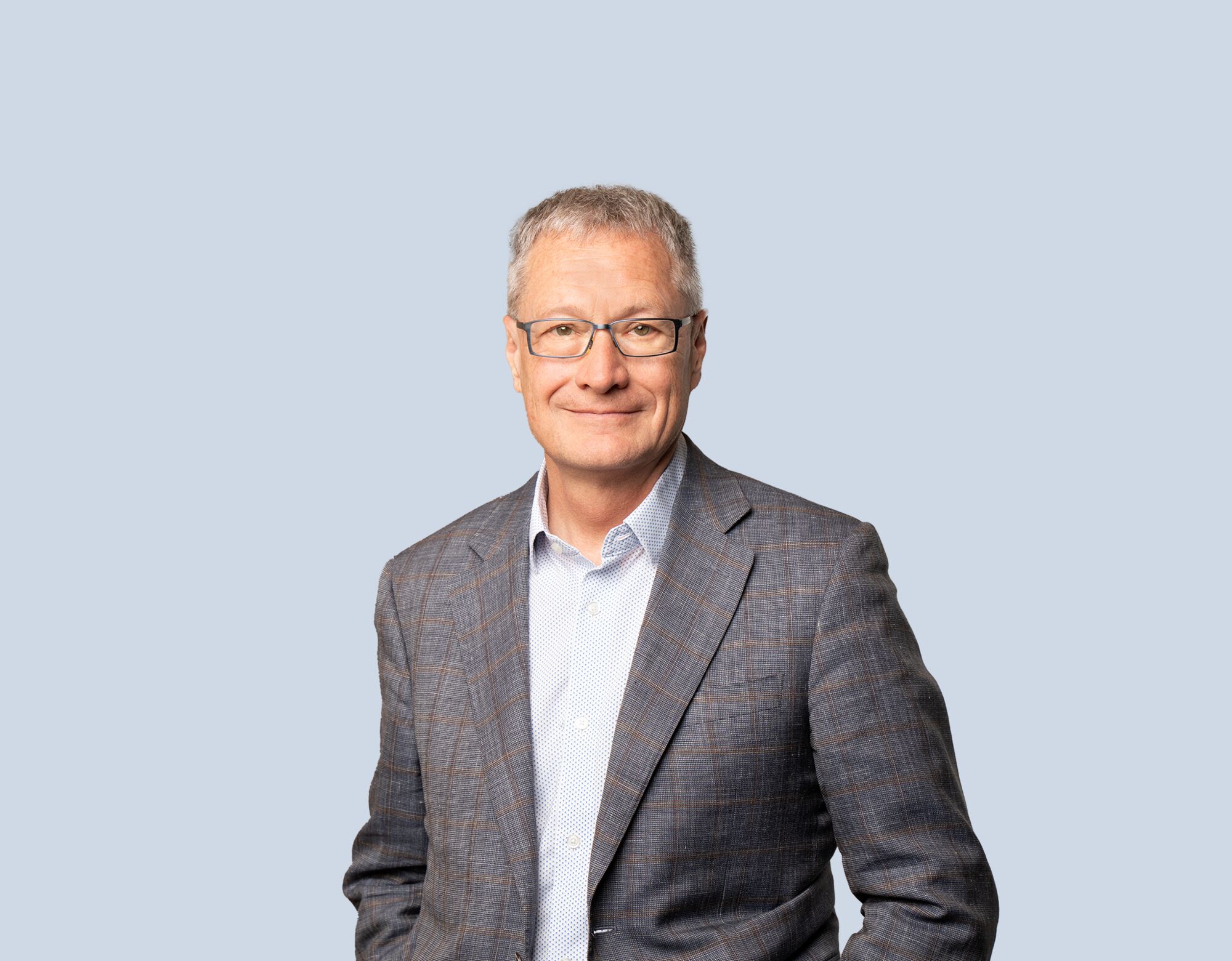 Jim McGill, member of Mattamy Asset Management's Board of Directors, wearing a grey blazer and smiling in front of a light blue background