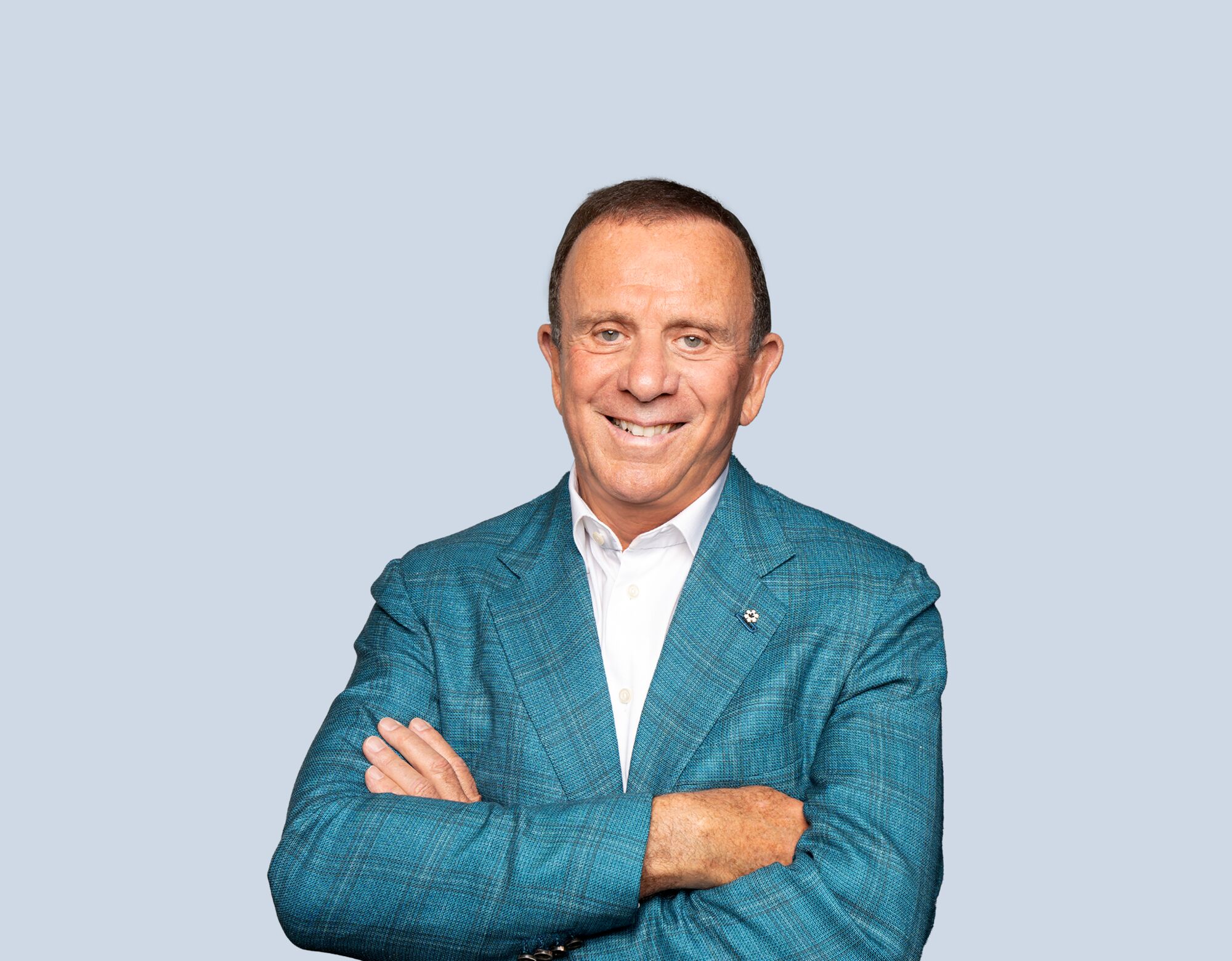 Peter Gilgan, member of Mattamy Asset Management's Board of Directors, wearing a blue blazer and smiling in front of a light blue background