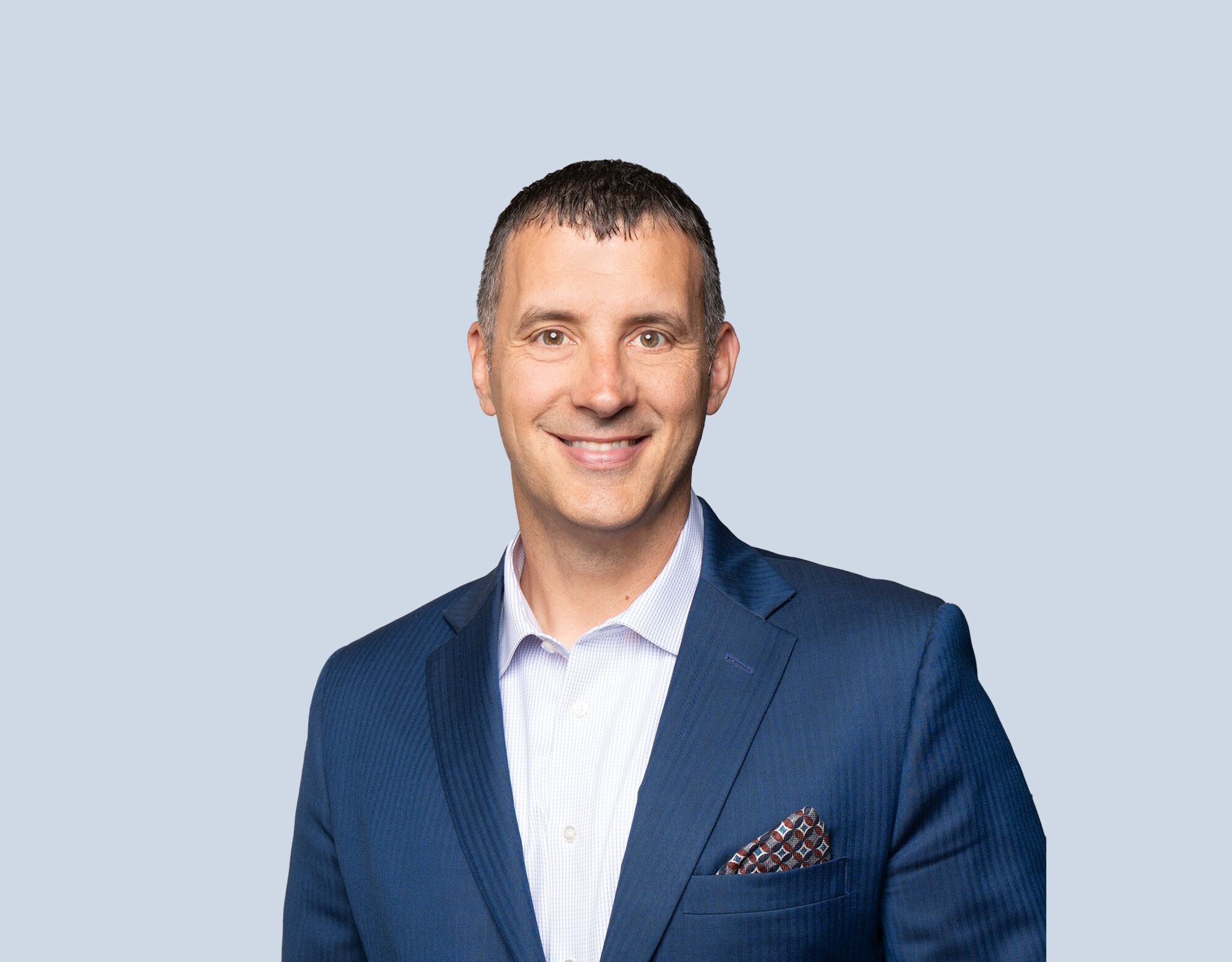 Bill Tofflemire, member of Mattamy Asset Management's Board of Directors, wearing a blue blazer and smiling in front of a light blue background