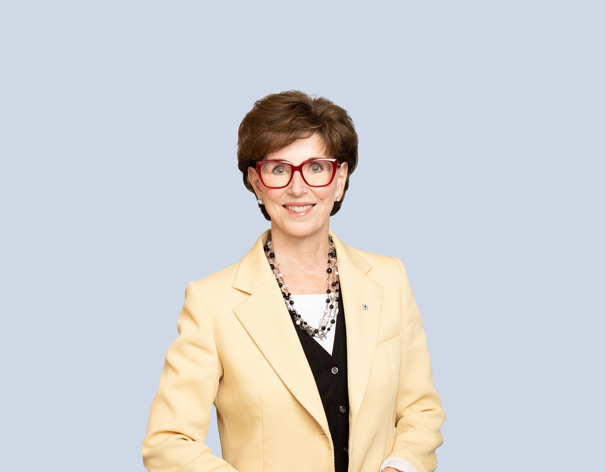 Katie Taylor, member of Mattamy Asset Management's Board of Directors, wearing a yellow blazer and smiling in front of a blue background