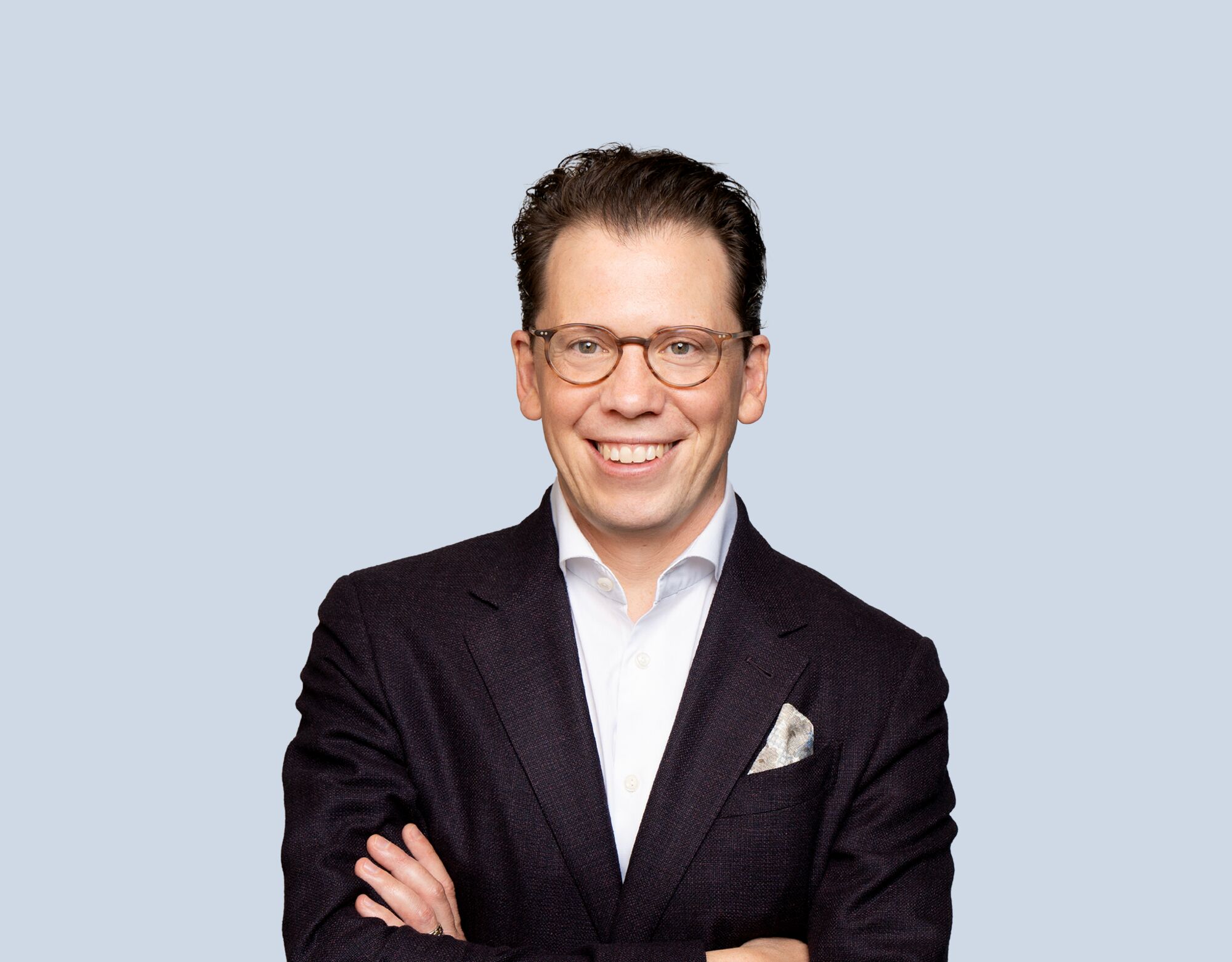 Luke Gilgan, member of Mattamy Asset Management's Board of Directors, wearing a dark blue blazer and smiling in front of a light blue background