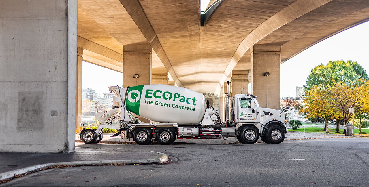 Lafarge white concrete truck parked under a bridge with green ECOPact logo on the back