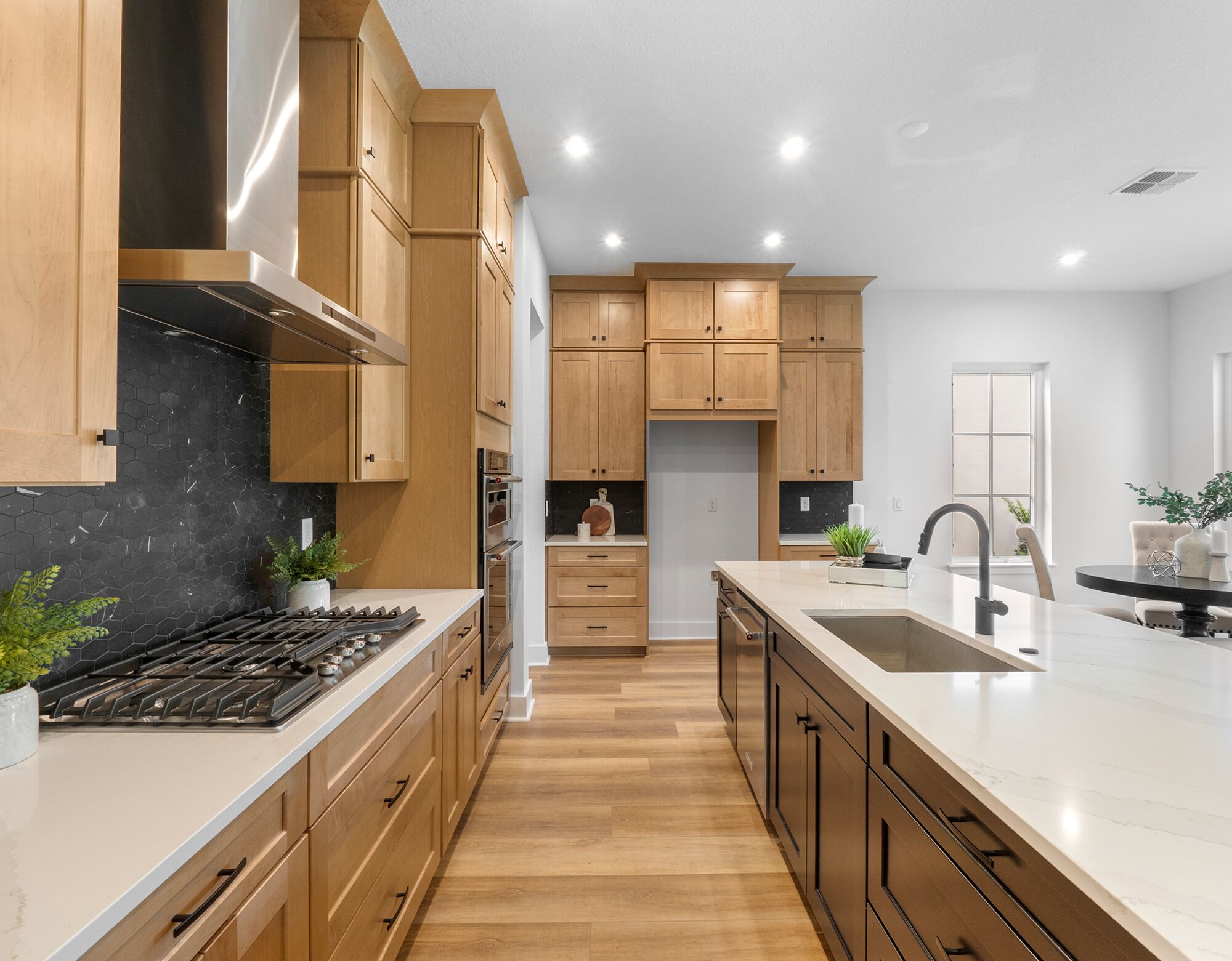  Kitchen with cooktop, oven, window, light wood cabinets, wood flooring and dark wood cabinets